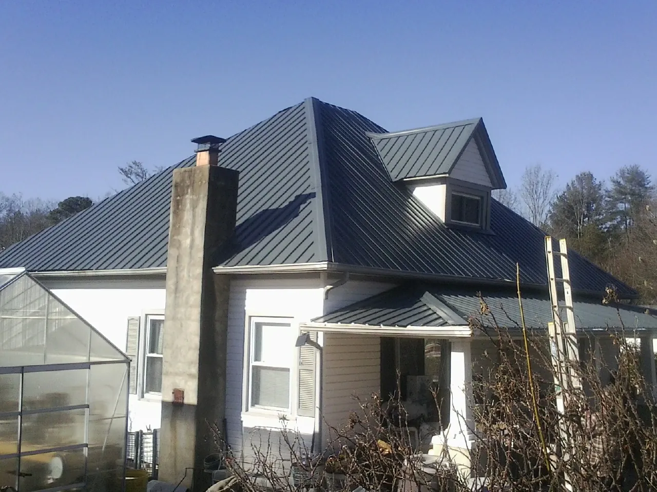 Dark blue standing seam metal roof on a white farmhouse with dormer — Slate & Tile Roof Repair by Roofing Brothers in Pitcairn