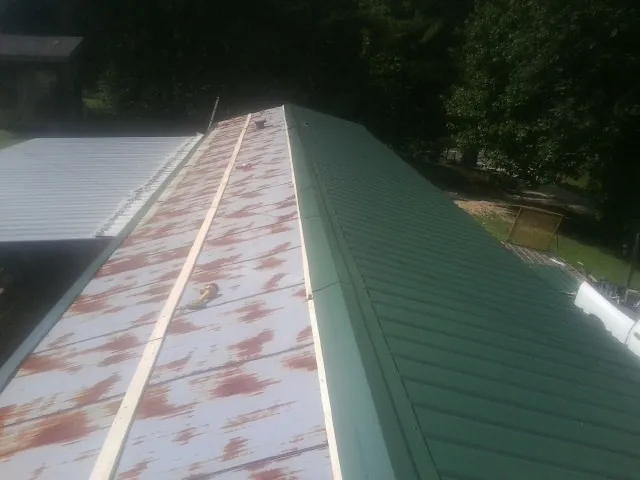 Old rusted panels beside newly installed green metal roofing — Wind Damage Roof Repair by Roofing Brothers in Pitcairn