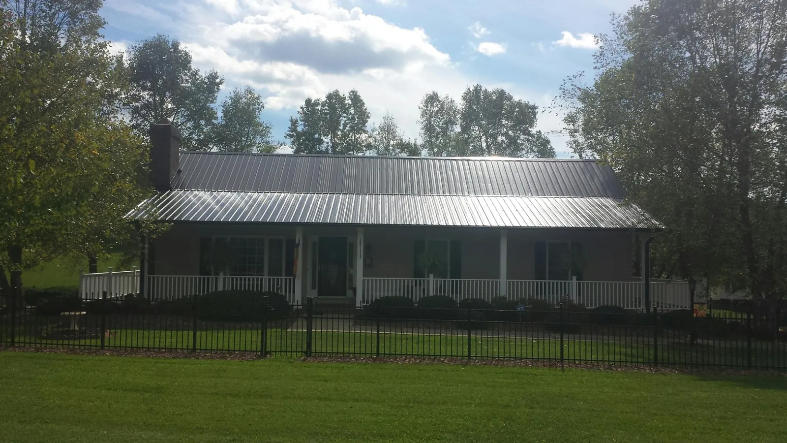 Gray metal roof on a brick ranch with a full width front porch — Gutter Guard Installation work by our crew in Pitcairn