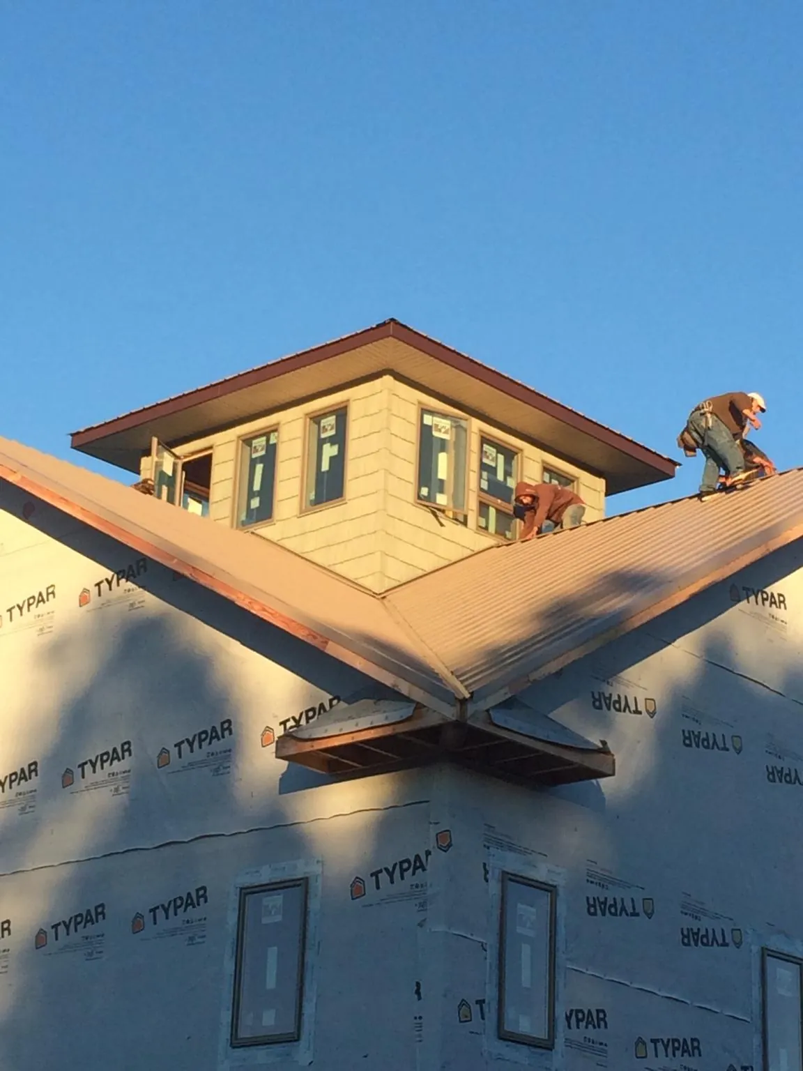 Roofers working around a rooftop cupola on a new metal roof at sunset — Roof Waterproofing in Pitcairn by Roofing Brothers